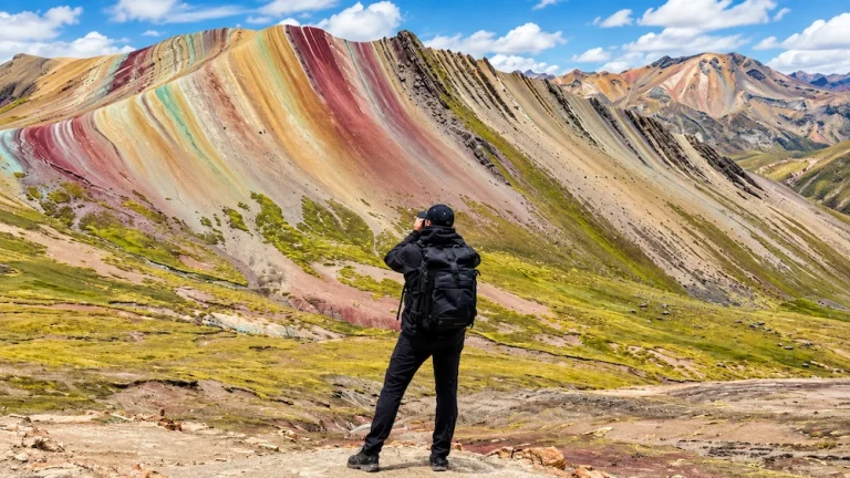 Caminhante fotografando as montanhas coloridas de Palcoyo em Cusco