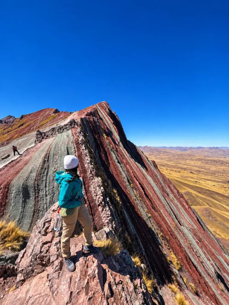 Traveler hiking along the colorful Pallay Punchu ridge in Cusco